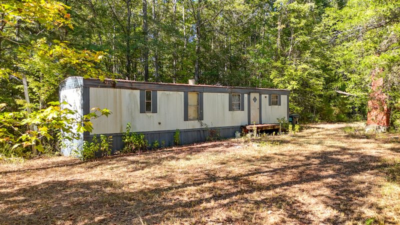 Single wide mobile home sitting in a clearing on the property