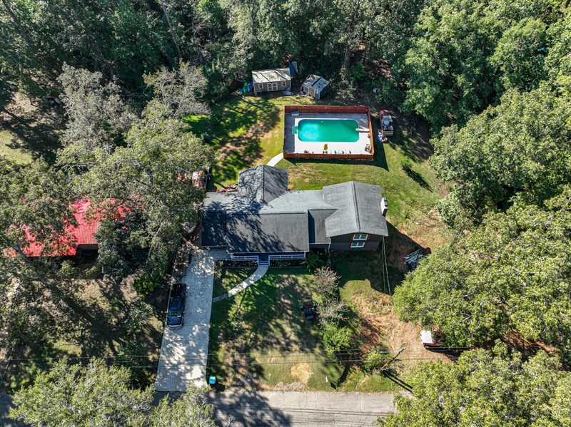 Aerial photo showing the house, the pool and the wooded lot around them