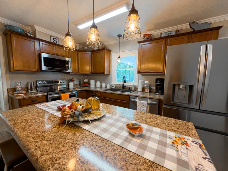 Kitchen with a granite island, stainless appliances and pendant lights