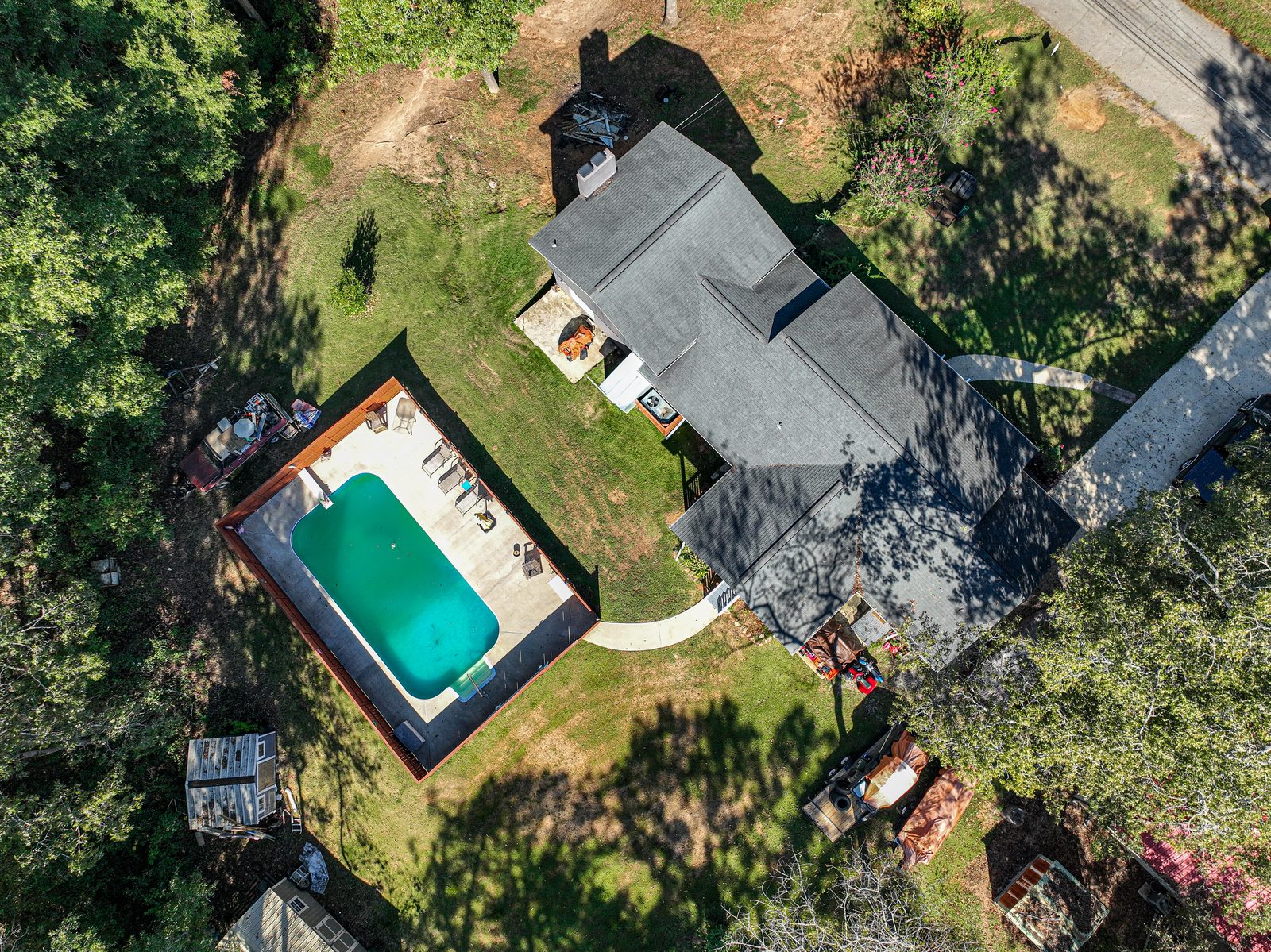 Overhead drone photo of the house roof and the fenced swimming pool beside it