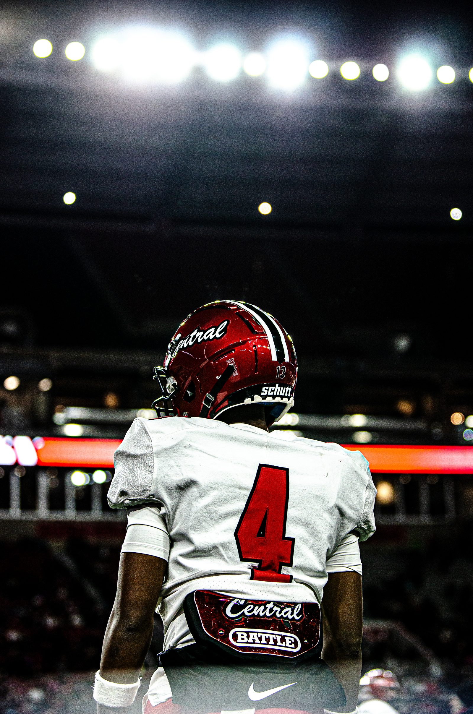 Football player number 4 seen from behind under stadium lights at night