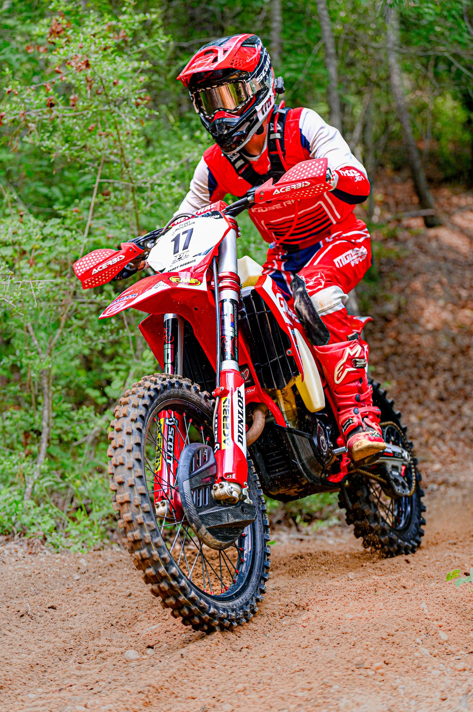 Motocross rider in red gear on a red bike at the start of a woods section