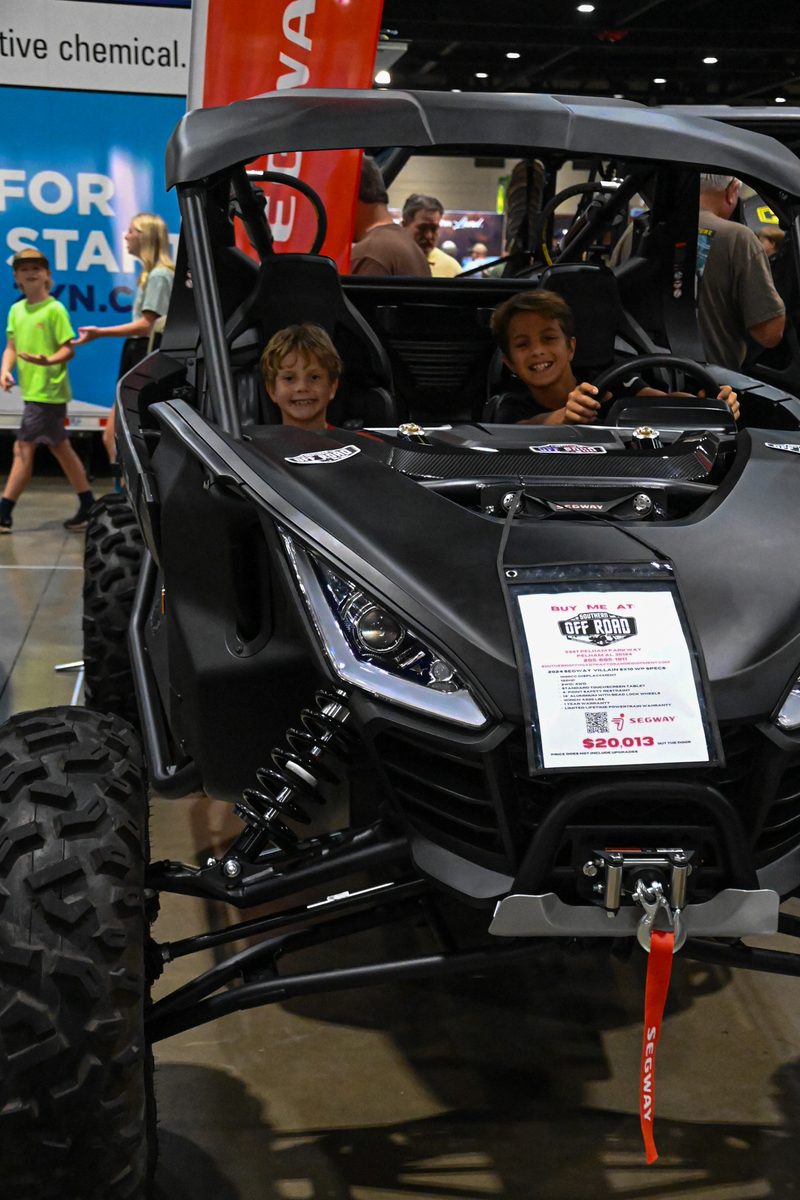 Side by side on display at a dealer event with customers seated inside