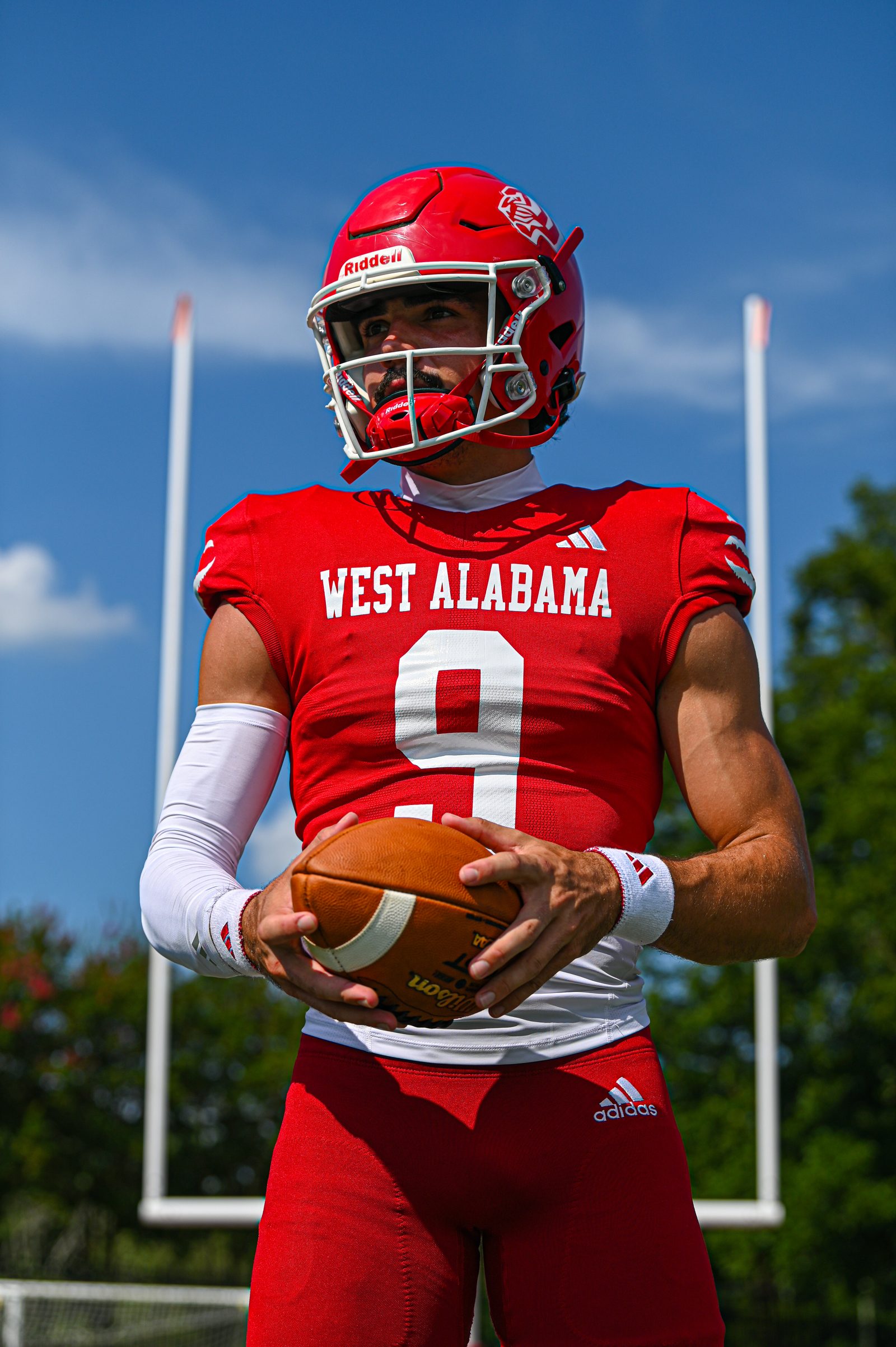 University of West Alabama quarterback in a red number 9 jersey holding a football on the field